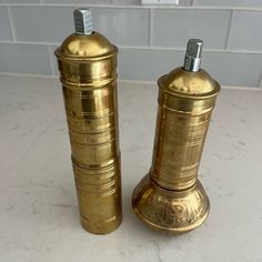 two brass salt and pepper shakers on a counter