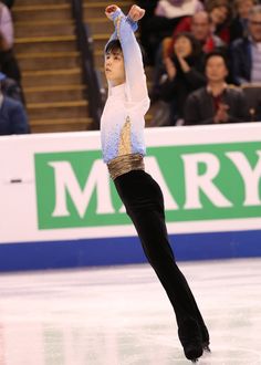 a woman skating on an ice rink with her arms in the air and one hand up