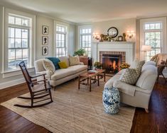 a living room filled with furniture and a fire place in front of two windows on either side of the fireplace