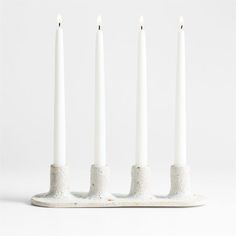 four white candles sitting on top of each other in front of a white background with no one around them