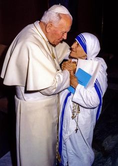 an older man and young woman dressed in white are greeting each other with their hands