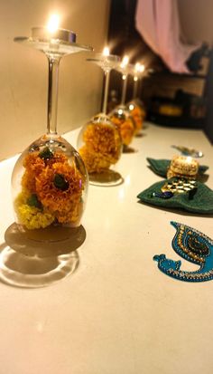 three wine glasses with flowers in them sitting on a table next to candles and other decorations