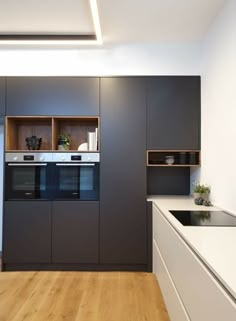 a modern kitchen with wood flooring and white counter tops, built in cupboards