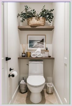 a white toilet sitting in a bathroom next to a shelf filled with towels and plants