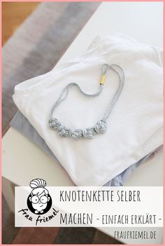 a white t - shirt sitting on top of a table next to a chain necklace