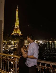 a man and woman standing next to each other in front of the eiffel tower