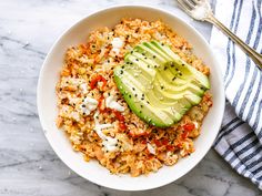 a white bowl filled with rice and topped with an avocado