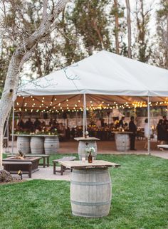 an outdoor event with barrels and tables