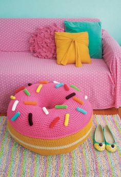 a pink knitted donut sitting on top of a rug in front of a couch