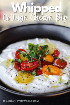 whipped cottage cheese dip in a black bowl with tomatoes and spinach on the side