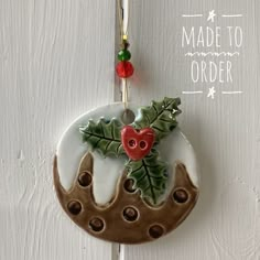 a ceramic ornament hanging from a hook on a white wooden door with holly and red berries