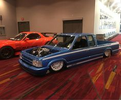 two cars are parked in a room with red carpet