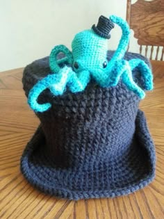 a crocheted hat with an octopus in it sitting on a wooden table next to a chair