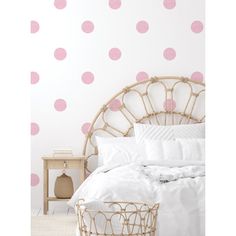 a white bed with pink polka dots on the wall