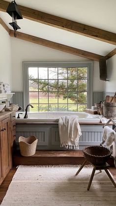 a bath room with a tub and a sink under a window next to a basket