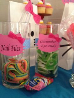 two clear vases filled with candy sitting on top of a blue tablecloth covered table