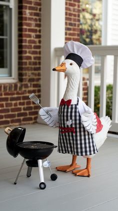 a statue of a duck with a chef's hat and apron cooking on a grill