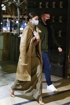 a woman walking down the street wearing a face mask