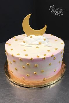 a white and pink cake with gold stars on it's side, sitting on top of a table