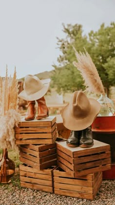 two hats are sitting on top of wooden crates in the middle of a gravel field