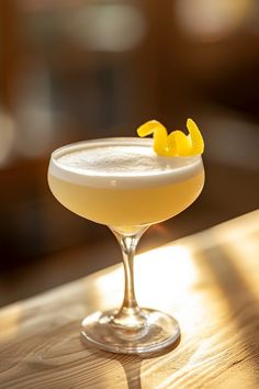 a cocktail with lemon garnish sitting on a wooden table