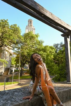 a woman is sitting on a ledge and smiling