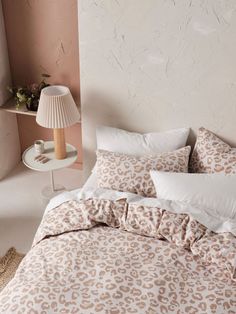 a bed with white and brown comforter next to a lamp on a table in a room