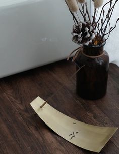 a vase filled with dried flowers on top of a wooden floor next to a white bath tub