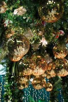 disco balls hanging from the ceiling in front of a christmas tree with garland and lights