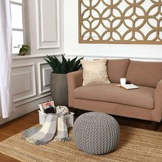 a living room with a couch, chair and ottoman on the floor next to a potted plant