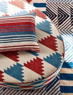 two pillows sitting on top of each other next to a blue, red and white blanket