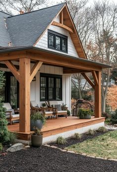 a small white house with black roof and wood trimmings on the front porch