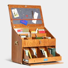 an open wooden box filled with lots of books and papers on top of a table