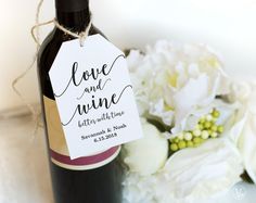 a bottle of wine with a tag on it sitting next to some flowers and a bouquet