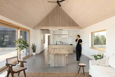 a woman standing in the middle of a living room next to a kitchen and dining area