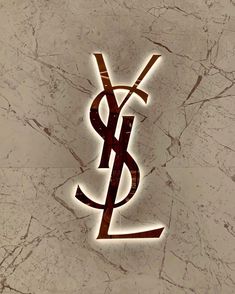 the ysl logo is lit up against a marble background with brown and white letters