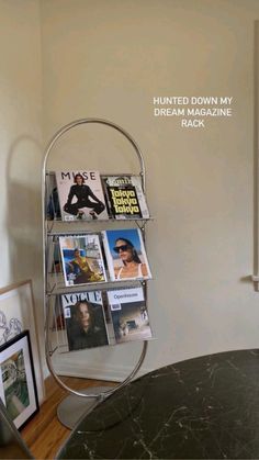 a magazine rack with magazines on it next to a table