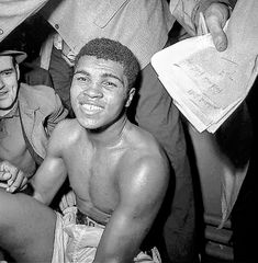 two men sitting next to each other in front of a group of people wearing hats