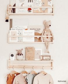 two wooden shelves with books and stuffed animals on them, one shelf is filled with children's clothing