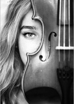 black and white photograph of a woman with long hair holding a violin in front of her face