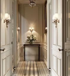 an elegant hallway with chandelier and flowers on the table in front of it