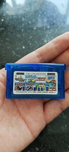 a hand holding a blue nintendo game case in it's left palm, with pictures of cars and trucks on the front