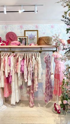 a room filled with lots of dresses and hats on top of a shelf next to a wall