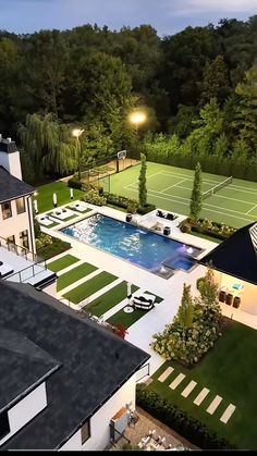 an aerial view of a house with a tennis court and swimming pool in the backyard