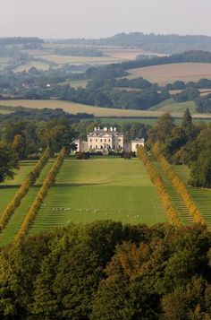 an aerial view of a large white house surrounded by green fields and trees with sheep grazing in the foreground