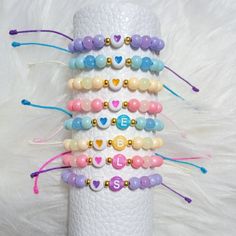 a stack of bracelets with beads and letters on them sitting on a white surface