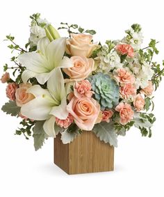 an arrangement of flowers in a wooden vase on a white background with greenery and succulents