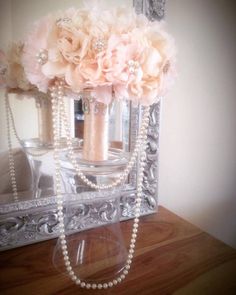 a vase filled with flowers and pearls sitting on top of a table next to a mirror