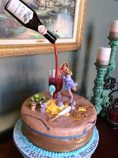 a birthday cake with a wine bottle pouring out of it and figurines on top