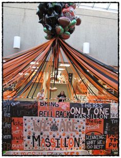 an orange and black decoration hanging from the ceiling in front of a building with words written on it